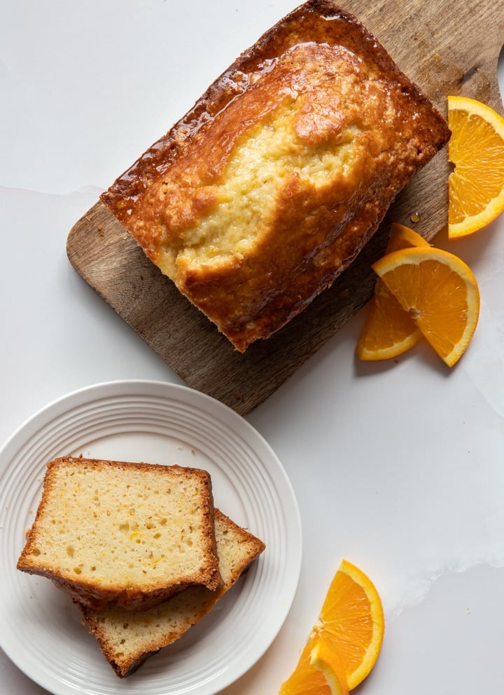 Orange bread on a wooden board and two slices on a white plate.