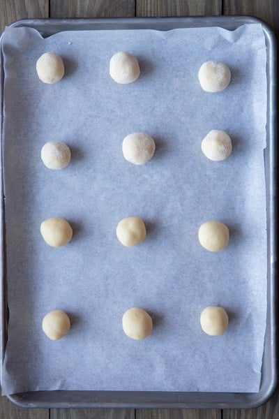 Dough rolled in balls on a parchment paper lined cookie sheet.