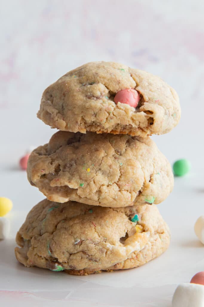 Three cookies one on top of the other with mini eggs and marshmallows around them.