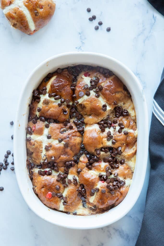 Hot cross buns pudding in a white baking dish.