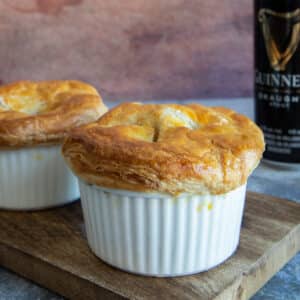 Two mini pies on a wooden board with a guinness can in the back.