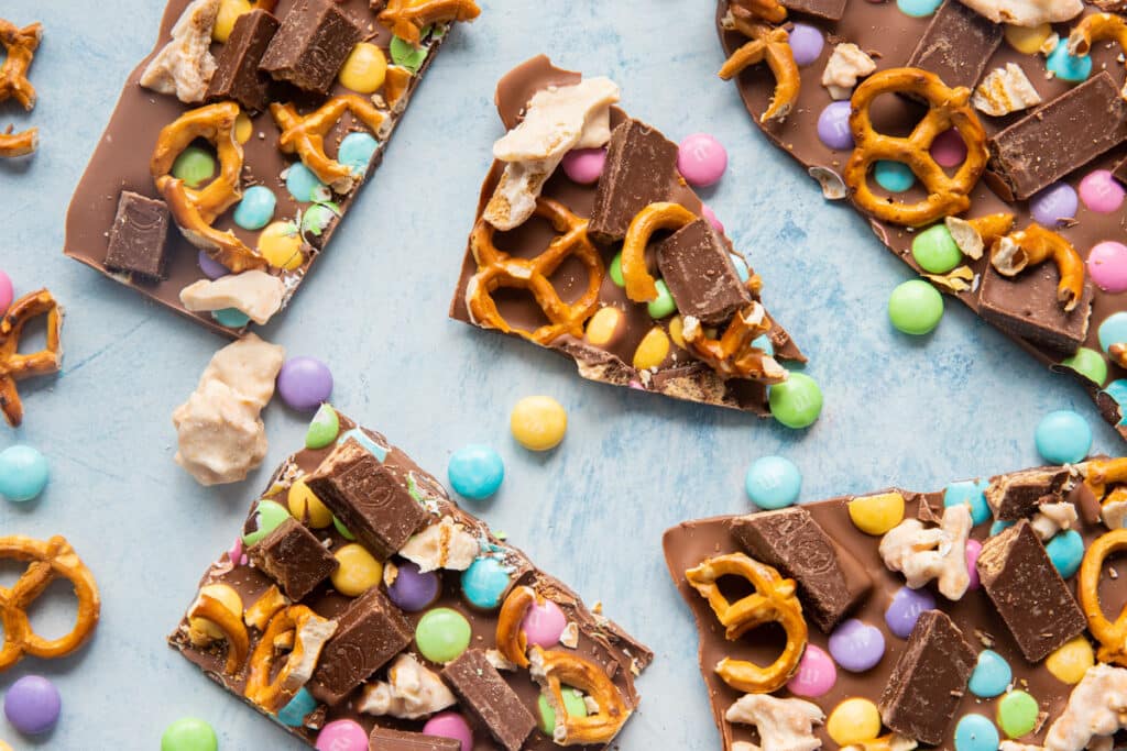 Chocolate bark pieces with smarties and pretzels scattered around.