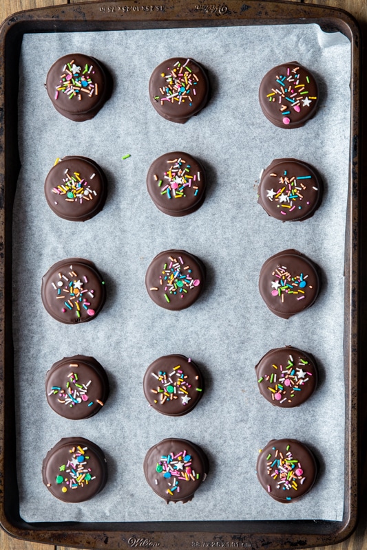 Chocolate covered oreos set after being chilled in the fridge on a baking sheet.