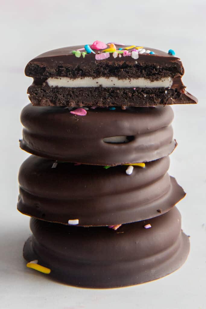 Four chocolate covered oreos on top of the other with the top one halved.