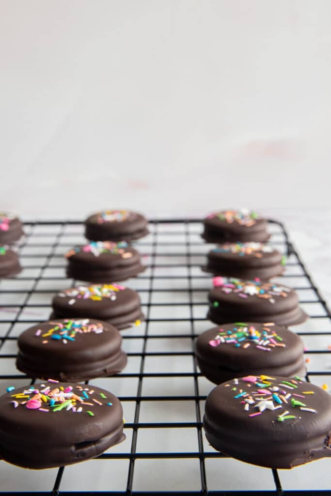 Chocolate oreos on a cooling rack.