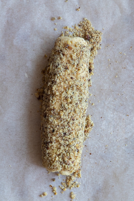 Cookie dough shaped into a log and rolled in crushed walnuts.