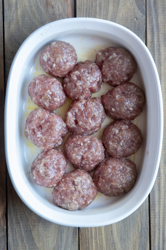 Sausage balls browned in a white casserole dish.