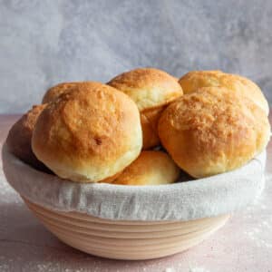 No-knead Bread rolls in a white and brown basket.