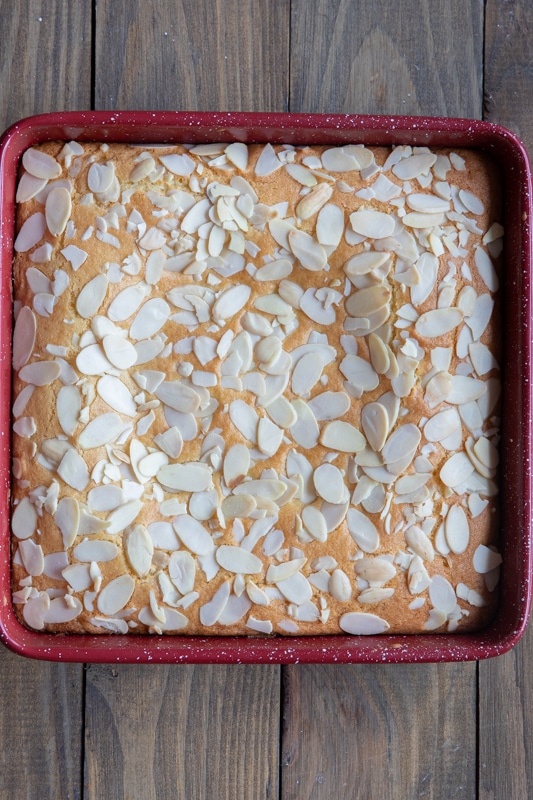 Baked Bakewell bars in a red baking pan.