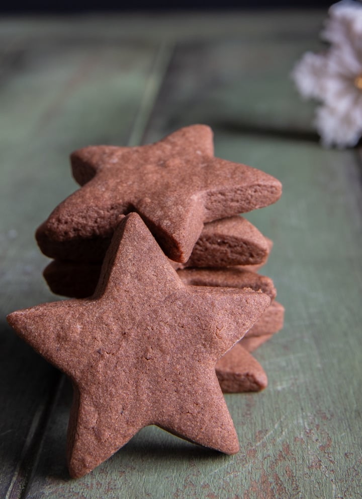 three chocolate cut out cookie stars stacked and one in front leaning on them.