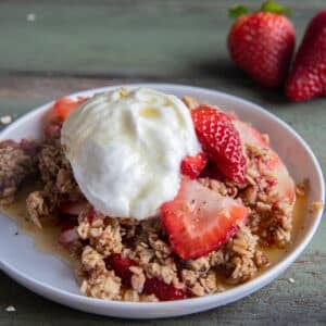 Pear & strawberry casserole on a white plate with a dollop of greek yogurt.