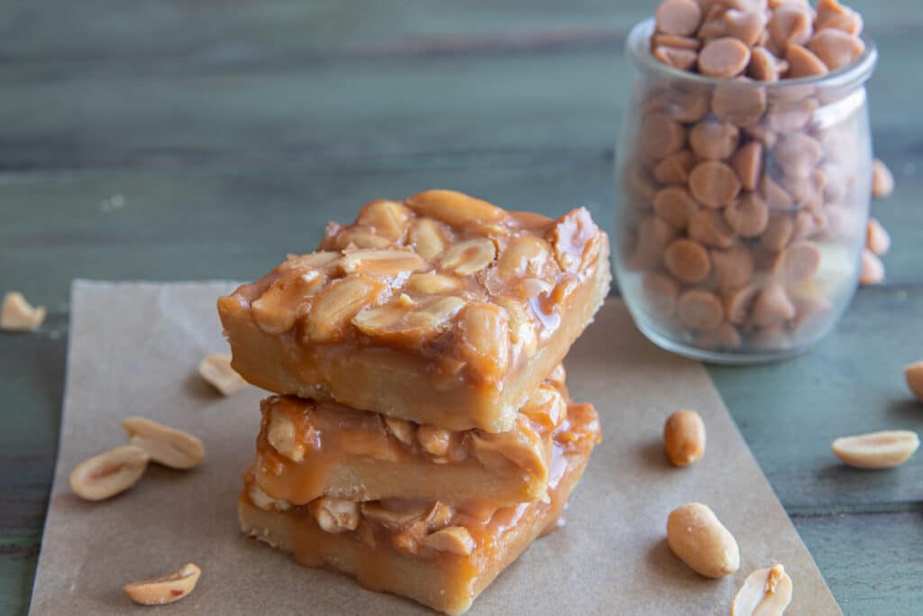 Three old fashioned peanut squares stacked on parchment paper.