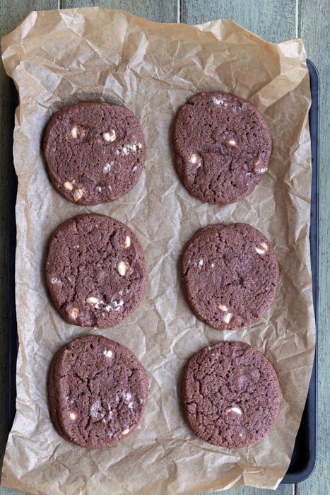 Baked crunchy white chocolate chip cookies on top of a baking sheet.