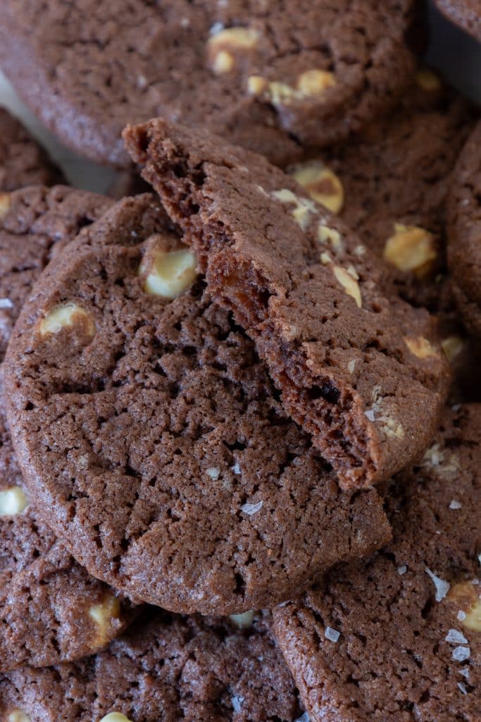 A broken chocolate chip cookie on top of other cookies.