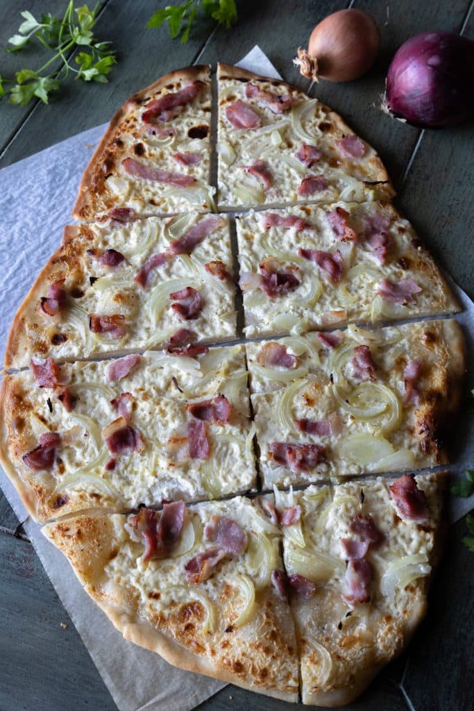 A Whole Flammkuchen on a sheet of parchment paper.