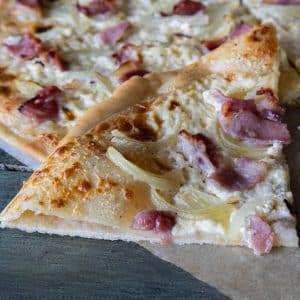 A slice of Flammkuchen on parchment paper.