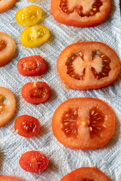 Tomatoes sliced and salted on a paper towel.