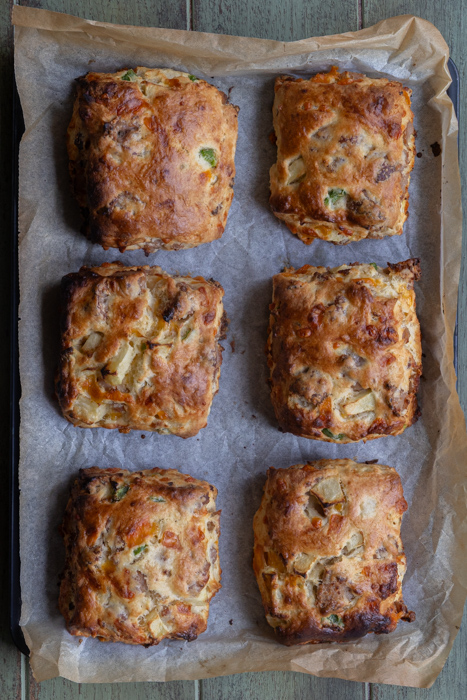 Baked jalapeno apple sausage cheddar biscuits on a baking sheet.