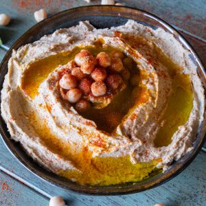 Homemade hummus in a dark bowl.